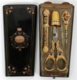 Lot#1208, FRENCH GOLD INLAID LACQUER NECESSAIRE WITH ENAMELED IMPLEMENTS, MID 19TH C., L 5"Lacquer case with gold inlay at the cover, opening to a velvet lined interior fitted with enameled gilt metal sewing scissors, thimble, needle case, and awl.  The awl is hallmarked with a ram's head (Paris) and an eagle.