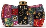Lot#1217, JUDITH LEIBER MULTICOLOR BOW MINAUDIERE, W 6 1/4"Bow shape with full bead multicolor crystals and cabochon accents, the crystal and cabochon push button opens to a two section interior with gold leather lining and a mirror. Stamped: Judith Leiber, New York. Measures W. 6 1/4" x 3 3/4" (19 1/4" to the chain shoulder strap).
