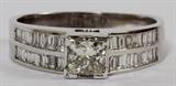 Lot#2057, 14KT WHITE GOLD 1.01CT DIAMOND GENTLEMAN'S RING, 7.4GR,Featuring a 1.01 carat princess cut at center, with an I-color, VS-2 clarity grading, flanked by 1.70 carats of baguette side diamonds, with a G-color, VS-2 clarity grading. The total weight of the ring is approximately 7.4 grams. Size 12.