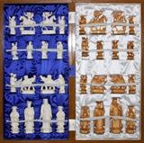 Lot#2290, CHINESE CARVED IVORY CHESS SET IN FITTED CHESSBOARD BOX, 32 CHESS PIECES, H OF PIECES 3 1/4" TO 6"Hand carved.  Box forms checker board and is 25" long.  White and tan stained chess pieces.  Modern.