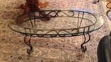 Oval glass top coffee table with green patina wrought iron base
