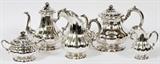Lot#1002 ,AUSTRIAN .800 SILVER TEA & COFFEE SET, EARLY 20TH C., FIVE PIECES, H 5"-9", L 27 3/4"Includes 1 coffee pot at 9", 1 teapot at 8 1/2", 1 pitcher at 8", 1 creamer, and 1 lidded sugar; all decorated with scrolled leaf form handles, having rose finials at the lids. Together with a non-matching rectangular Rogers silver plated tray, #2792, measuring L. 27 3/4". Measuring approximately 124.97tr.oz. in total weight. Early 20th Century.