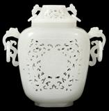 Lot#1004, CHINESE CARVED WHITE JADE COVERED URN, H 6 3/4", W 6 1/2"Carved pierced body, missing base cap. Having double handles and lid.