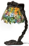 Lot#1015, E. THOMASSON, ART NOUVEAU STYLE LEADED GLASS FIGURAL LAMP, H 29 1/2", W 14"Figure of a female nude draped over the leaded glass shade of the lamp. Signed, "E. Thomasson" at base.