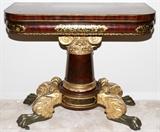 Lot#2318, ATTR. TO JOSEPH MEEKS & SON, NEW YORK, MAHOGANY FLIP TOP GAMES TABLE, C.1825, H 30 3/4", L 36 1/2"Attributed to Joseph Meeks and Son, New York, circa 1825.  Classical carved gilded, stenciled and ebonized flip top games table. Purchased ca. 1818 by James Weeks.  Ex. Estate of James Huggins Weeks and Susan Weeks.  Purchased from the estate they built named 'Lilacs' in Yaphank, Long Island, NY. D 18 1/4" closed, D 37" opened.  Mahogany flip top with stenciled edge.  Fruit and foliated stencil on apron. Carved scrolling and leaf capital.  Tapered column. Four carved scrolling leaf and paw feet on castors.