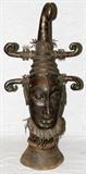 Lot#22, AFRICAN TRIBAL BRONZE HEAD, H 44", W 20"Raised on an elongated neck, having a stylized scrolled headpiece, decorated with frayed leather along the neck and top. Measures H. 44" x 20". Property from the Henry Stallings II Collection, Detroit, MI.