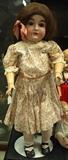 Kestner #164 27" Doll (1820 – 1938) - Ball joint composition body, Blue sleep eyes, molded brows, painted upper & lower lashes, open mouth w/4-upper teeth, Original long brown human-hair wig, Original shoes, socks & underwear, Replaced pink floral cotton print dress