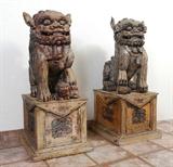 Lot 1110:  PAIR LARGE CARVED WOODEN FOO DOGS: Palace sized carved foo dogs, each with matching stand. Traces of paint decoration remains. Larger of 2 dogs measure 26 1/2'' x 15'' x 20'', stands 16'' x 18 1/4'' x 22 1/4''.
CONDITION: Weathering, wood and paint loss, sold as-is.