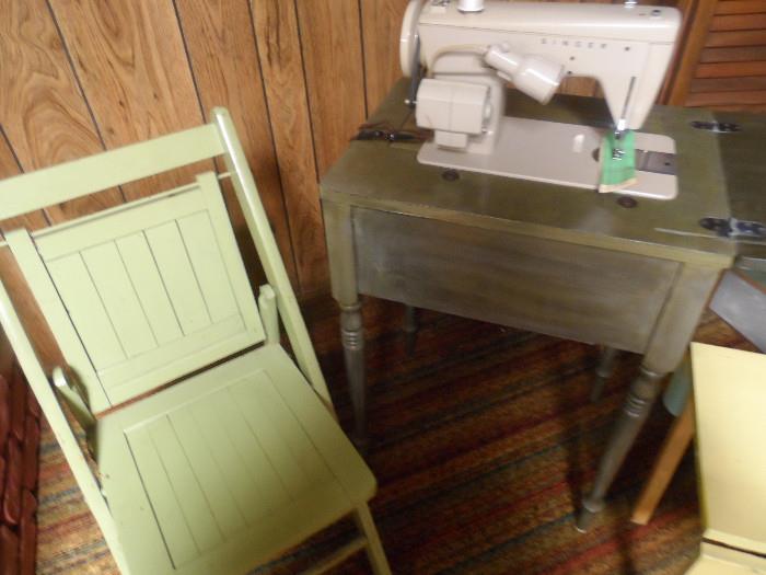 Singer sewing machine in cabinet with stool.