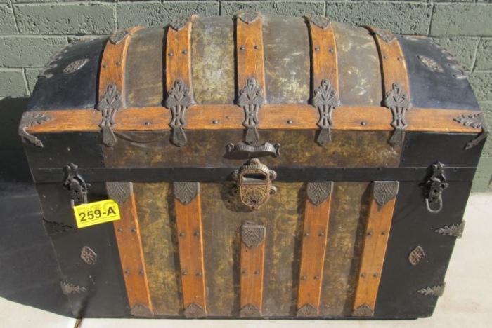 Lot#:	259a
Description:	Large Vintage Dome Top Saratoga Steamer Trunk
Large vintage wooden camel back, dome top Saratoga steamer chest. This dome top trunk features vertical wooden slats with decorative and protective metal embellishments on edges and corners. It securely locks with 2 latches and one central lock; all hardware appears intact including the outside leather handles. Completely covered with tin metal; some has a nice embossed pattern. The inside is lined in brown paper and has all its complex compartment trays with decorative embellishments including chromolithographs of roses and pansies plus a British fox hunt scene with a decorative red, white and blue geometric border. It is fairly clean with some staining odor; but could easily be re-lined in a fabric of choice. The outside is in excellent condition with normal wear denting and scuff marks. Unknown maker; it has some patent marks on the hardware. Measures 28" height x 36" length x 20" deep. 
From the internet: “A dome