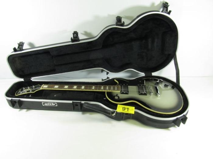 Lot#:	91
Description:	Les Paul Custom Epiphone Electric Guitar & Case
Awesome Les Paul Custom Plus Line Epiphone electric guitar with black hard case. In superb condition; it features multiple bindings around the back and top of the body and has a bound headstock with a split-diamond inlay. Now discontinued this custom model is Serial No. EE070707574, and has a stunning flame maple top and vintage Sunburst finish. Excellent condition with SKB Orange, California, TSA approved locking protective hard case with black interior. Other specifications include:
- Mahogany back with top maple veneer
- Signature split-diamond pearloid inlay on the headstock
- Rosewood fingerboard with block pearloid inlays on the fretboard
- glued in neck joint 
- 5 ply white binding 
- Silver toned hardware
Tag Words: Musical Instrument, Band, Rock N' Roll, Music, Gibson, tuxedo