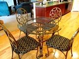 Ornate Cafe Set...Glass & Metal Round Table with Glass Top and wrought iron base with spider web design and nicely scrolled legs, four (4) matching wrought iron chairs with spider design backs and cushion seats