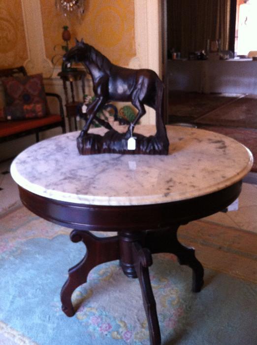   horse statue atop a marble top/round entry table