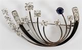 Lot#2074, GUSTAV MERZ, LADY'S 18 KT, DIAMOND AND SAPPHIRE BROOCH..Gustav Merz - Zurich.  Featuring seventeen diamonds and a single sapphire set in 18KT white gold.
