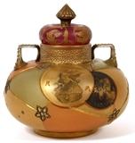 Lot#1019, MT. WASHINGTON GLASS CO. 'ROYAL FLEMISH' VASE WITH COVER, C. 1890-1900, H 6"Covered vase having two handles and lavishly decorated with four medallions. One medallion has a profile of royalty and letters "R" and  "F".  Another disc has a crowned lion. Base has an internal stress mark -  does not have a ridge on inside or outside.  Measures H.5 3/4", W.5 1/2".