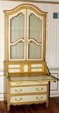 Lot#1157, BAKER FURNITURE CO. DECORATED SECRETARY DESK, H 87", W 38", D 19 1/2".Painted ivory with gold accents, labeled within a drawer. Bookcase top over slant front desk with three long drawers at base. Venetian influence.