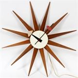 Lot#256, HERMAN MILLER, MODERN SPIKE WALL CLOCK, W 18"Starburst/spike design by George Nelson for the Herman Miller clock Company. Circular brass housing with white face, gray and orange painted hands and a red seconds hand, with twelve tapered walnut spikes.