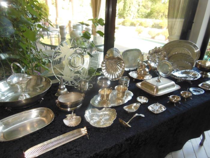A Dorothy Thorpe Etched Charger surround by an assortment of Silverplate and Sterling Table Articles.