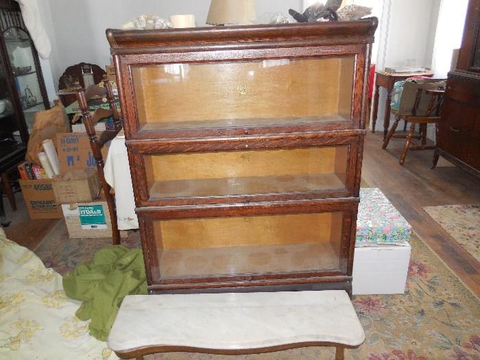 Oak three section book case.  In the front of the book case is the marble base to a large mirror. 