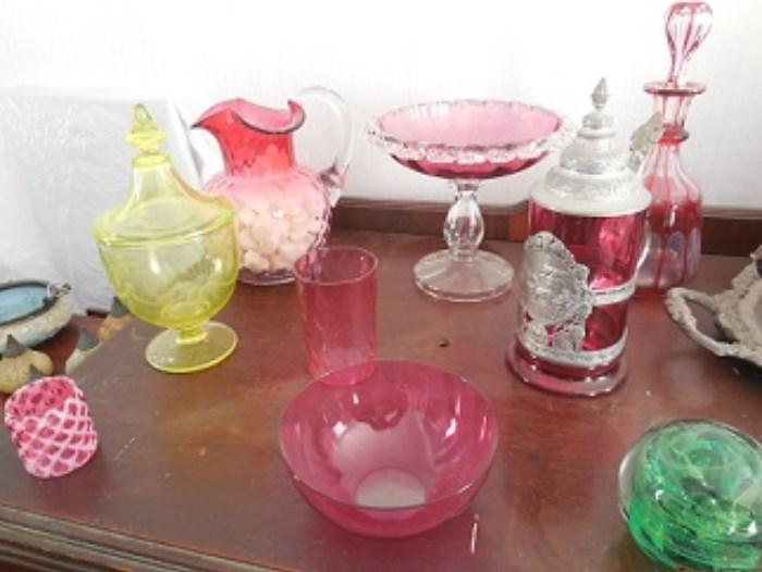 The clear to Ruby Pitcher on the left back is hand blown. The cranberry glass compote has applied detail to the rim and is hand blown.  The cut to clear decanter is blown.  Other blown pieces are the bowl, cup and small art glass piece in right corner.  The 