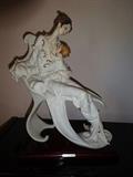 A piece in cast porcelain called "Mother and Child" by Giuseppe Armani. It is hand painted depicting a mother holding her child while seated. It is 10" wide by 7" deep at the base and stands 14.5" high.