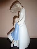 This piece by Lladro is entitled "Windswept Mother and Child" and depicts a mother and daughter. It is hand painted porcelain and stands 12" high by 8" long by 4" wide.