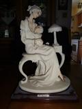 Entitled "Mother and Child" by Giuseppe Armani, this piece depicts a mother seated upon a stool, and holding a child. Made of hand painted porcelain, it stands at 10" high by 7"