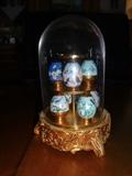A collection of Faberge' type eggs in a display holder entitled "Sapphire Garden". The piece is 6" high by 4" diameter. Each egg is approximately 1" in size.