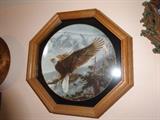 An octangle wood and glass framed collectors plate that is 12" in diameter. It is entitled "Eagle Soaring" and depicts a bald eagle alighting from a branch.