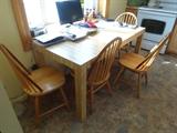 A laminate dining table 60" by 30" with four Windsor chairs. The chairs are solid oak blonde wood. The table also has a laminate butcher block.