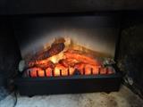 An electric fireplace grill that lights up orange red and gives off heat. It is 24" wide by 19" high and 5" deep.