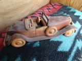 A hand carved boat tail roadster Packard in maple by Jack Benton. It is 11" by 4" by 5"