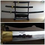 A set of three samurai swords with an acrylic stand. They are made in Taiwan and of stainless steel. The largest is 41" long by 4" by 5"