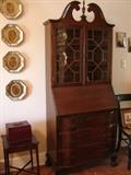 Mid size secretary bookcase with swan pediment (also known as "broken pediment") and finial bonnet. Drop front writing surface. Undulating drawer fronts and claw and ball feet. Mahogany.