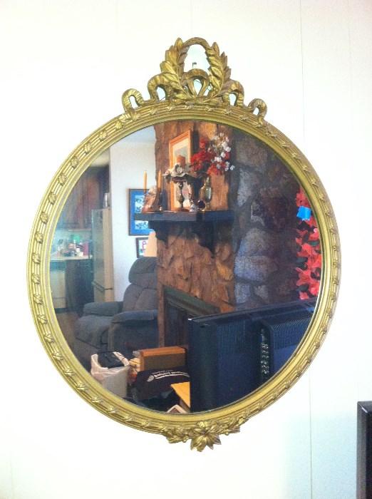 Ornate round mirror, painted gold frame.
