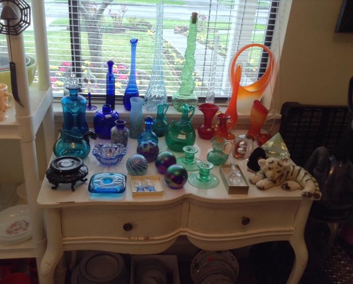 Colorful glass by Blenko, Viking, Pilgrim & more.  Note Holmegaard pinched "Kluk" decanter in back left corner.  All displayed on a shabby chic writing desk...