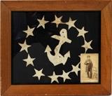 Lot#193, CANTON OF NAUTICAL ENSIGN, WITH PHOTOGRAPH OF SAILOR, H 10", W 12"Canton of a nautical ensign, with hand stitched fouled anchor, encircled by stars. In lower right corner, there is a photograph of a sailor standing beside a chair, measuring H 4", W 2 1/2".