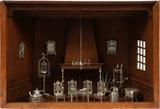Lot#1013, DUTCH SILVER MINIATURE FURNITURE & ACCESSORIES, 15 PIECES, ENCASED WITHIN A WOODEN ROOM//Four side chairs, center table, settee, chandelier, bird cage, fireplace tools, flax wheel, wall curio, two frames, tea pot, coffee pot. 15 items. Probably Dutch made.