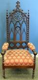 Lot#1349, GOTHIC STYLE CARVED WALNUT & UPHOLSTERED CATHEDRAL CHAIR//Having turned arms and legs with a cathedral arched top. Padded upholstered arms and a cushioned seat.