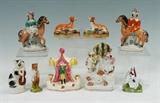 Lot 1325:  9 STAFFORDSHIRE FIGURINES: Ann assembled collection to include 2 whippet dogs, figures on horsebacks, cat with guitar, bear with musical instrument, figure in tent, figures with faux clock (6'' h. x 3 1/2''). Estate of Elton Hoyt II