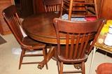 Round oak claw-foot dining table with four oak chairs.