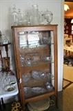 Antique oak display cabinet and vintage crystal serving pieces and decanters.