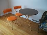Bistro set with Mid Mod shiny orange vinyl chairs by Gallo Original Iron Works.