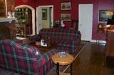 View of the large den- pictured a plaid sofa and loveseat - hardly seen is a great looking mahogany tray table on stand - 
