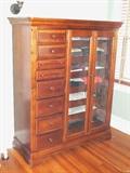 Alexander Julian Home Colours Haberdasher Chest, Beveled Glass Doors w/ Seven Tray Drawers Flanked by Eight Varied Depth Drawers w/ Marquetry Inlay, Tortoise Shell Effect Round Drawer Pulls, Bracket Feet, 52"W X 21"D X 62"H