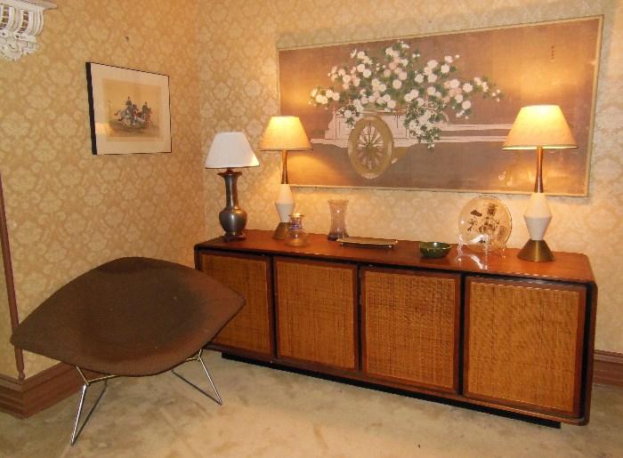 A 1950's Bertoia "Diamond" Chair in front of a Mid-Century Credenza i SOLD; an Original 'Flower Cart' Painting by Robert Crowder SOLD!; and a cool pair of Mid-Century Lamps and a Pewter Vase w/ Brass Overlay Vase converted into a Lamp.