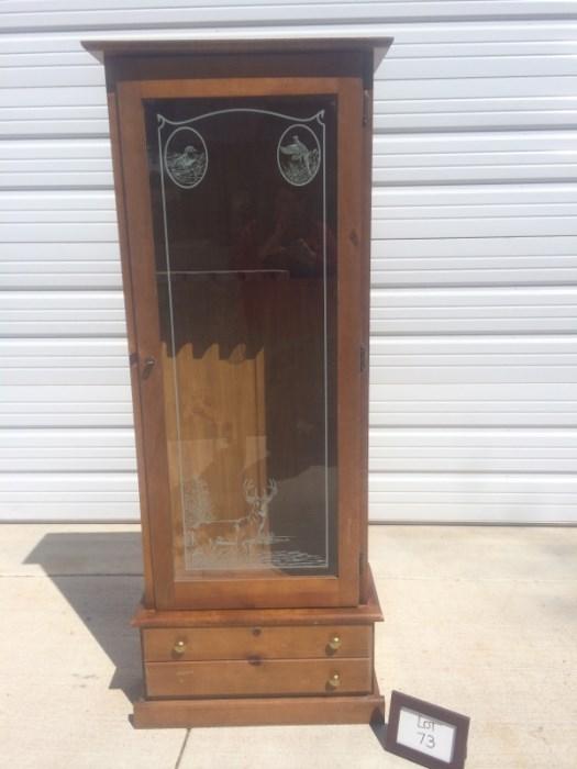 Wooden gun cabinet with decorative glass front and storage space at the base. Comes with key to lock the top and bottom spaces. Overall condition is good.