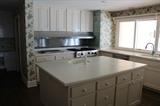 kitchen island with corian counter tops, cabinet with pull out shelves, sink and faucet