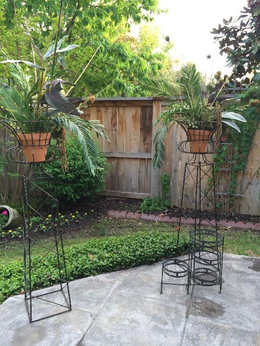 two tall metal plant stands with plants included.