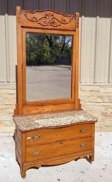 Beautiful American oak dresser with a removable granite top. Large ornately carved mirror. This piece has a matching high back oak bed that will also be available at auction.